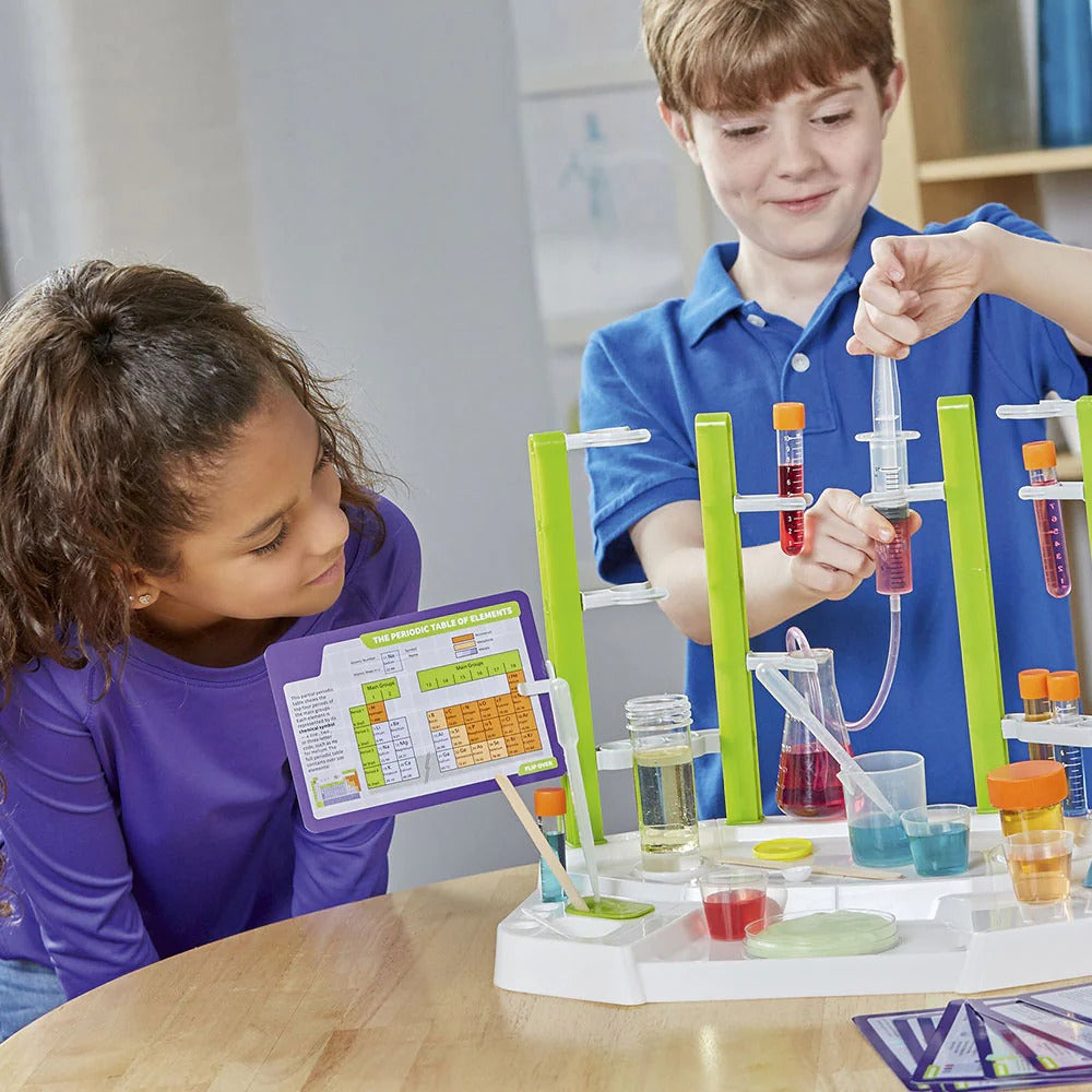 Two children conducting a science experiment with test tubes and a clipboard in a classroom setting.